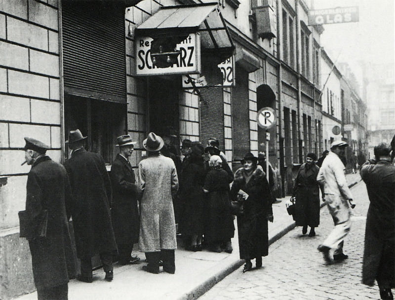 Historische Ansicht: Passanten vor dem verwüsteten Restaurant Schwarz