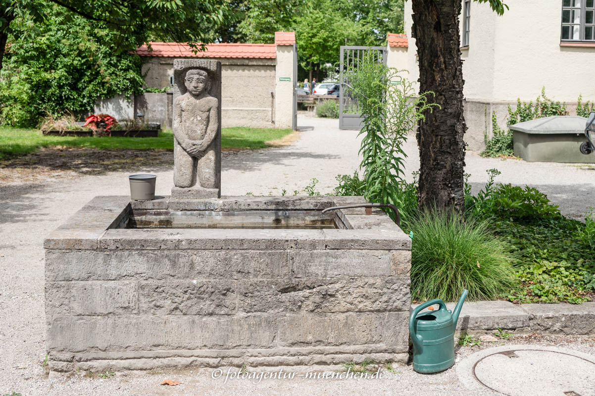 Knieender nackter Mann am Brunnen